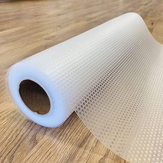 a roll of white plastic mesh sitting on top of a wooden floor