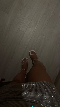 a woman's feet with shiny shoes on and one foot in the middle of her body