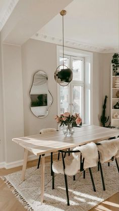 a dining room table with chairs and a vase filled with flowers on top of it