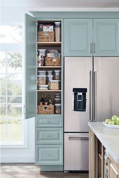 a kitchen with blue cabinets and stainless steel refrigerator freezer next to an open window