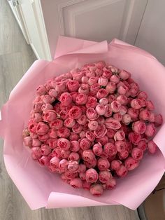 a bouquet of pink roses in a paper wrapper on the floor next to a door