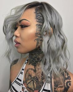 a woman with grey hair and tattoos on her face