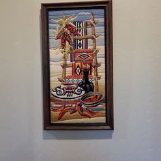 a painting hanging on the wall next to a vase with flowers and birds in it