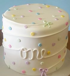 a white cake with polka dots and the word one on it