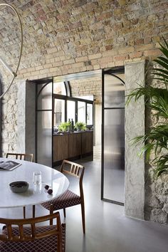 a dining room table with chairs and a potted plant in the corner next to it