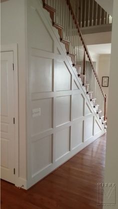 an empty room with wooden floors and white walls, stairs leading to the second floor