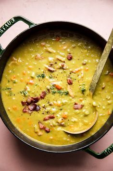 a pot filled with soup on top of a pink tablecloth next to a wooden spoon