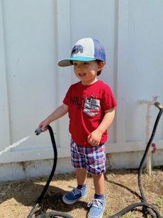 a young boy standing next to a hose