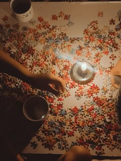 two people sitting at a table with puzzle pieces on it and one person holding a lit candle