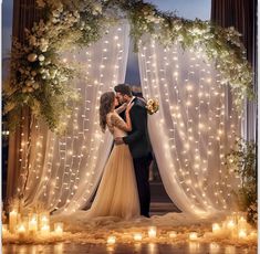 a bride and groom kissing in front of a wedding arch decorated with fairy lights at night