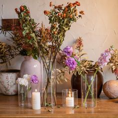 several vases with flowers and candles on a table