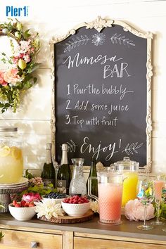 a bar with drinks and flowers on the counter next to a chalkboard that says dinner bar