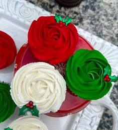 three cupcakes with white frosting and green icing on a red plate