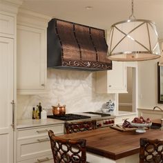 a kitchen with white cabinets and an island in front of a stove top oven above it