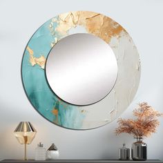 a round mirror sitting on top of a wooden table next to a vase and lamp