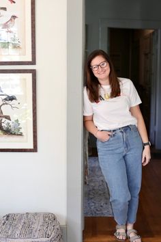 a woman standing next to a wall with pictures on it