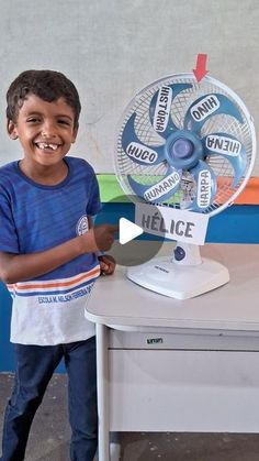 a little boy standing next to a table with a fan on it's side