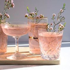 three glasses with flowers in them sitting on a table