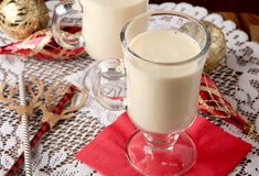 two glasses of milk sitting on top of a table next to christmas decorations and gold ornaments