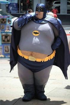 a man in a batman costume is standing on the sidewalk