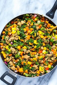 a skillet filled with meat and vegetables on top of a marble countertop next to a spatula