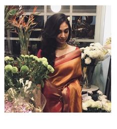 a woman is standing in front of some flowers