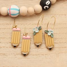 three pairs of earrings sitting on top of a wooden table next to bead necklaces