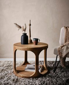 a wooden table sitting on top of a shaggy rug next to a chair and vase