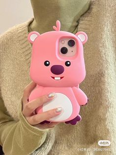 a woman holding a pink phone case with a bear on it's back,