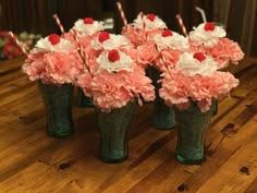 several vases with flowers and candy canes in them sitting on a wooden table