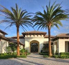 a house with palm trees in front of it and a walkway leading to the front door