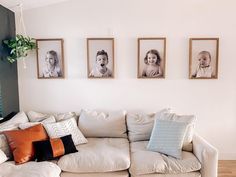 a living room filled with white couches and pictures on the wall above them,