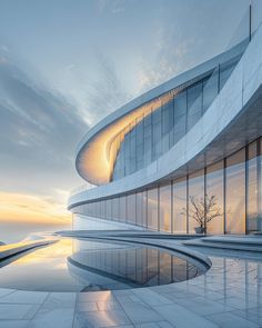 a building with a pool in front of it and the sun going down behind it