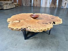 a wooden table with a bowl sitting on it's center piece in front of stacks of logs