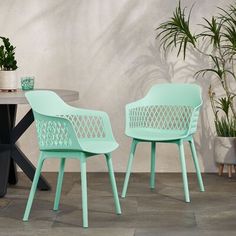 two chairs sitting next to each other near a table and potted plant on the floor