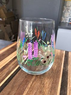 a glass with flowers painted on it sitting on a table