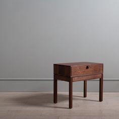 a small wooden table sitting on top of a hard wood floor next to a gray wall