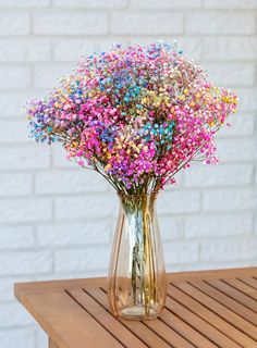 a vase filled with colorful flowers on top of a wooden table