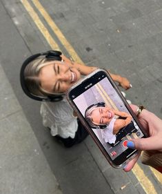 a woman taking a selfie with her cell phone while standing on the side walk