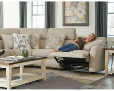 a woman laying on top of a couch in a living room next to a coffee table