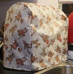 a kitchen sink with a oven mitt covered in reindeers and santa's hats