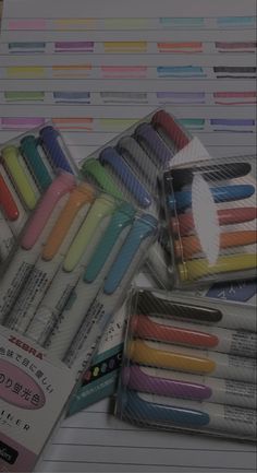 many different colored pens are in a package on the table next to some papers and pencils