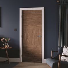 a living room with blue walls and a wooden door in the center, next to a chair