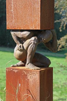 a statue is sitting on top of a wooden block in the middle of a field