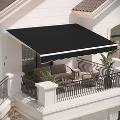 an awning over a patio with furniture and plants on the balcony area outside it