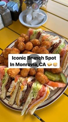 a plate full of sandwiches and tater tots sitting on a table with a sign that reads iconic brunch spot in monroe, ca