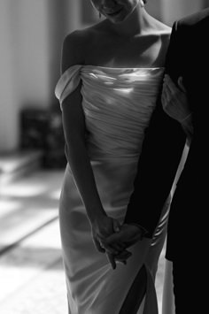 black and white photograph of a woman in a dress holding the hand of a man