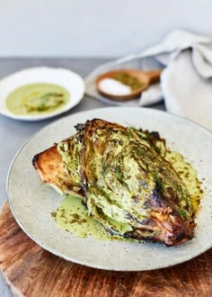 a white plate topped with meat covered in pesto sauce and garnished with parsley