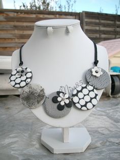 a white and black necklace with flowers on it sitting on top of a mannequin