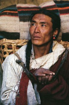 a man with long braids sitting in front of a basket